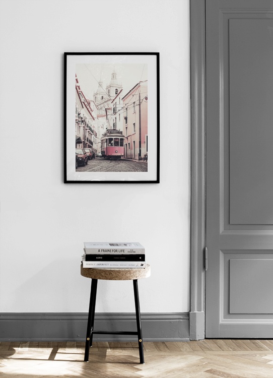  – Fotografia de um elétrico rosa a passar no meio de uma rua cheia de prédios em tons rosa e branco