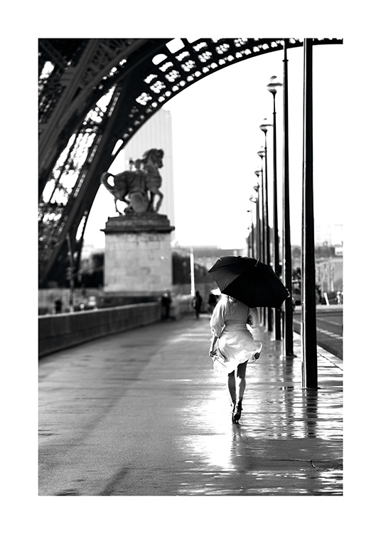  – Fotografia a preto e branco de uma mulher a caminhas com um guarda – chuva por baixo da Torre Eiffel