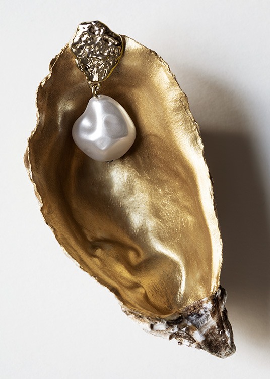  – Fotografia de uma concha com interior em dourado e um brinco em pérola em cima, sob um fundo cinza claro