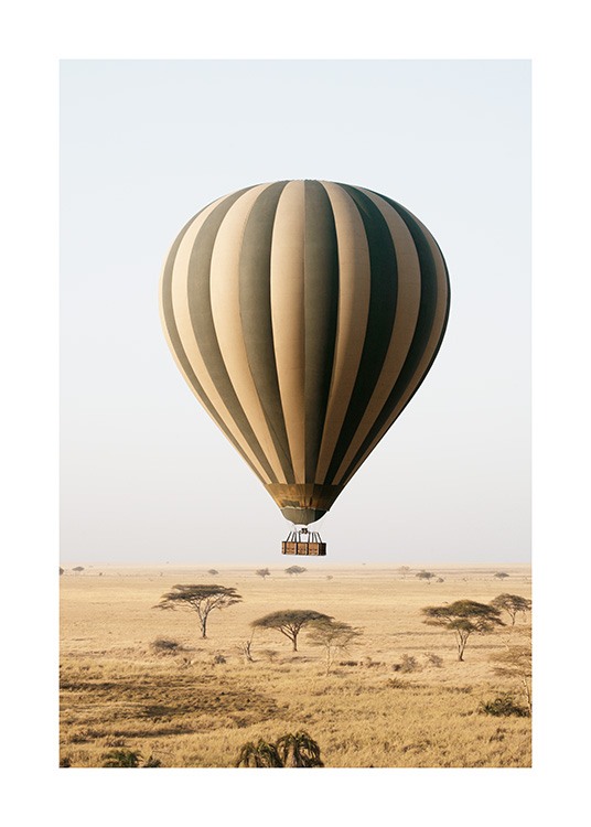  – Fotografia de um balão de ar quente com riscas em amarelo e verde a voar sobre uma savana