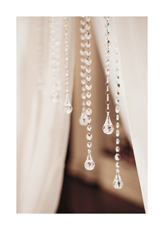  – Fotografia em pormenor de pendentes em cristal com cortinas brancas de fundo